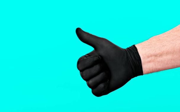 Чоловіча рука в рукавичці, великий палець піднятий, показуючи знак добре. Концепція захисту від бактерій та вірусів, особистої безпеки та гігієни
. - Фото, зображення