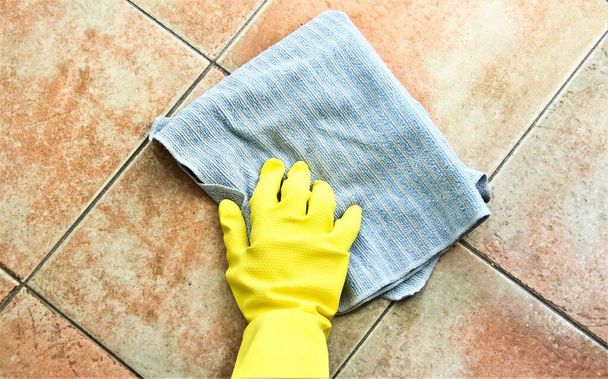 Mão na luva protetora telhas de limpeza chão com pano
 - Foto, Imagem