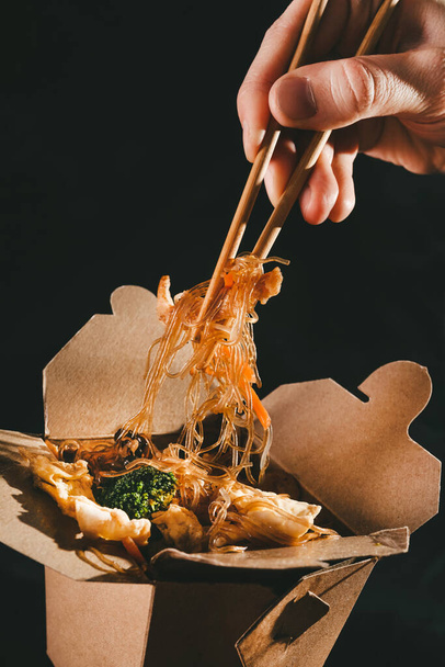 funchoza with seafood. man eating chopsticks spaghetti with vegetables. food delivery. takeaway food. Chinese food. japanese noodles - Photo, image