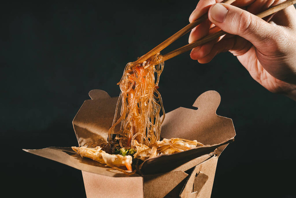 funchoza with seafood. man eating chopsticks spaghetti with vegetables. food delivery. takeaway food. Chinese food. japanese noodles - Photo, Image