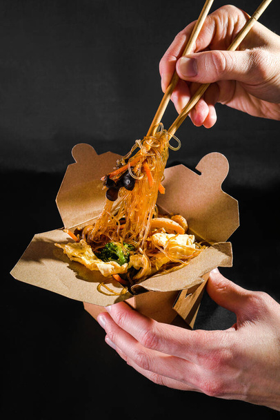 funchoza με θαλασσινά. Ο άνθρωπος τρώει σπαγγέτι με λαχανικά. παράδοση τροφίμων. φαγητό για το φαγητό. Κινέζικο φαγητό. γιαπωνέζικα νουντλς - Φωτογραφία, εικόνα