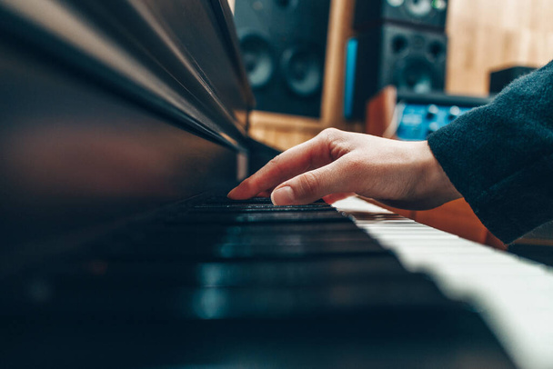 Kobieca ręka na klawiszach fortepianu w studiu nagraniowym. Nagrywaj utwór muzyczny. - Zdjęcie, obraz