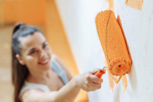 アパートの修理。幸せな若い女性はオレンジの色で壁をペイント - 写真・画像