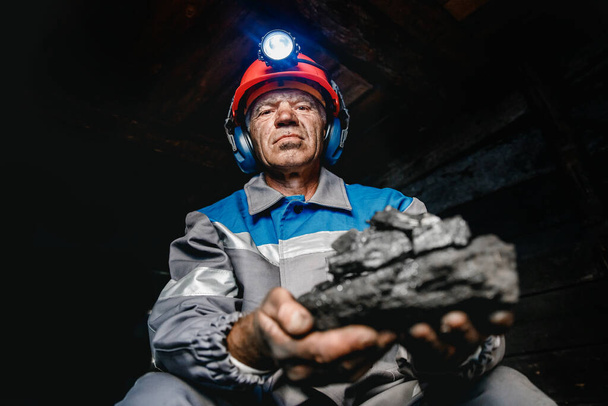 Madenci portresi kömürcüsü miğferinde fenerle yeraltı madeninde. Endüstriyel mühendis - Fotoğraf, Görsel