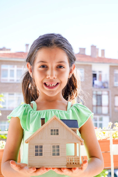 Little girl holding wooden house model. Hosing, mortgage, family and financial concept.  Image - Photo, Image
