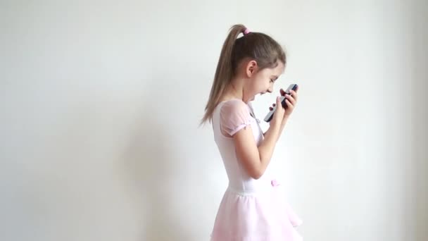 Mała emocjonalna, kaukaska dziewczyna, patrząca na telefon i śmiejąca się, robiąca selfie i pozująca do zdjęć, rozmawiająca z przyjaciółmi w sieci. Koncepcja komunikacji i blogowania online. - Materiał filmowy, wideo