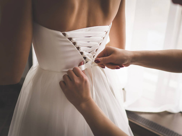 Mother ties the bride's dress on the wedding day - Foto, afbeelding