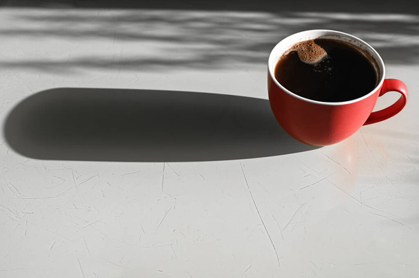 tasse rouge avec une ombre. Longue ombre d'une tasse de café
. - Photo, image