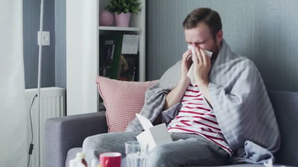 Man blowing his nose while sitting on a couch in the living room - Filmagem, Vídeo