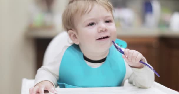 Infant boy eats with a spoon - Imágenes, Vídeo