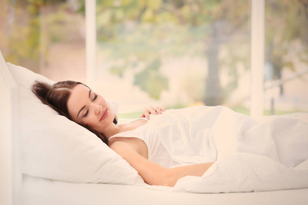 Νεαρή ελκυστική γυναίκα κοιμάται στην κρεβατοκάμαρα - Φωτογραφία, εικόνα
