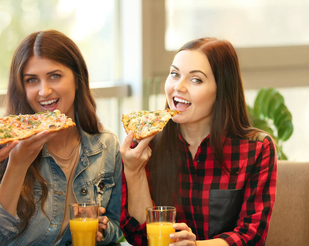 Cheerful young women eating tasty pizza in cafe - Фото, изображение