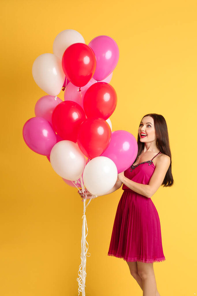 Hermosa joven con globos de aire sobre fondo amarillo
 - Foto, imagen