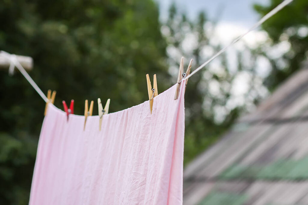 Freshly washed bed linen hanging on the rope outdoors. Clothes drying in rural yard. - Photo, Image
