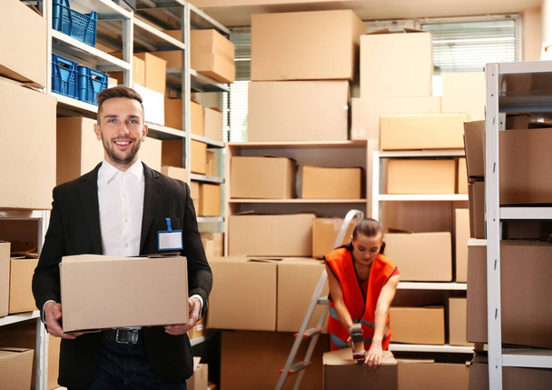 Young businessman holding box at warehouse - Photo, Image