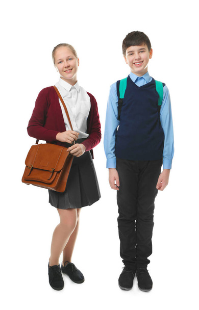 Милый мальчик и девочка в школьной форме стоят на белом фоне
 - Фото, изображение