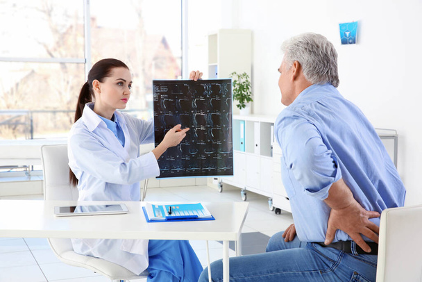 Женщина-ортопед осматривает старшего мужчину в клинике
 - Фото, изображение