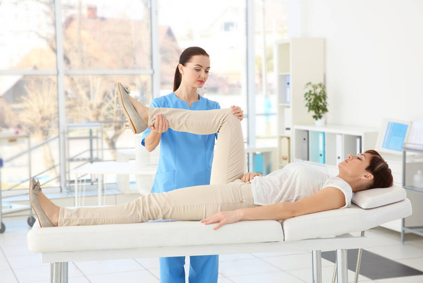 Klinikte orta yaşlı bir kadına masaj yapan kadın ortopedist. - Fotoğraf, Görsel