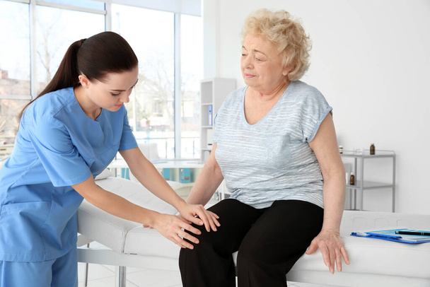 Female orthopedist examining senior woman in clinic - Foto, immagini