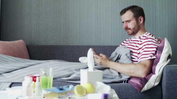 Хворий молодий чоловік використовує телефон і дме ніс з носовичкою
 - Кадри, відео