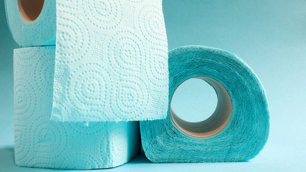 Modrá role moderního toaletního papíru na modrém pozadí. Papírový výrobek na papírovém rukávu, používaný pro hygienické účely z celulózy s odřezky pro snadné trhání. Razítkovaný výkres. - Fotografie, Obrázek