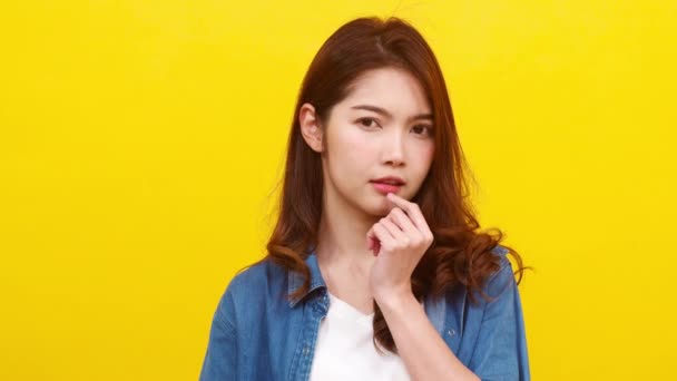Smiling adorable Asian female with positive expression, smiles broadly, dressed in casual clothing and looking at the camera over yellow background. Happy adorable glad woman rejoices success. - Footage, Video