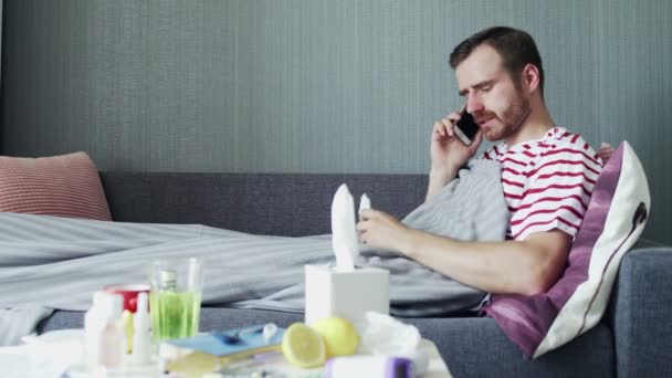 Nemocný mladý muž mluví po telefonu doma - Záběry, video