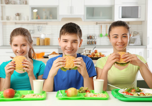 Children eating delicious sandwiches in school canteen - Fotó, kép