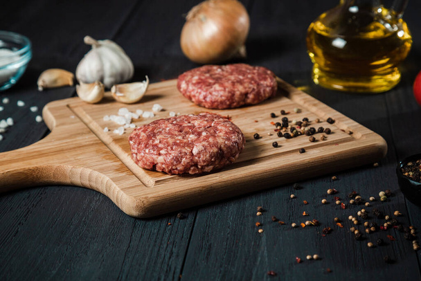 Cutlets from minced meat with the ingredients on the black wooden table. Home cooking. - Fotoğraf, Görsel