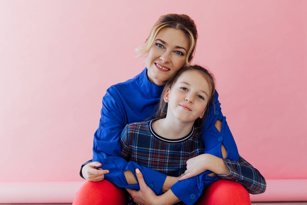 Mom and daughter family cuddling on pink background - Foto, immagini