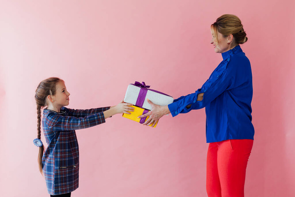 Anya és lánya család adni egymásnak ajándékokat rózsaszín alapon - Fotó, kép
