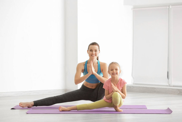 Mother and daughter doing exercise indoors - Foto, afbeelding