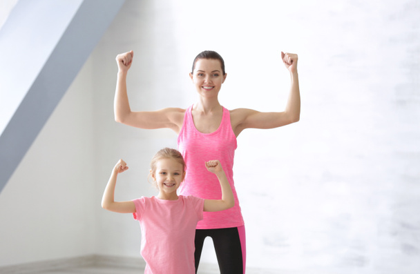 Мать и дочь показывают сильные руки в спортзале
 - Фото, изображение