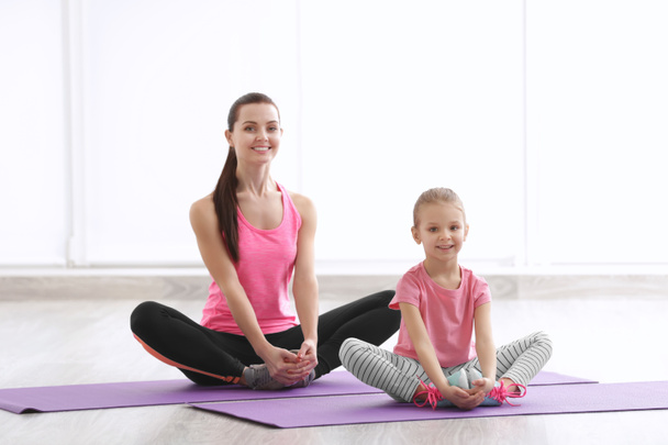 Mother and daughter doing exercise indoors - Фото, изображение