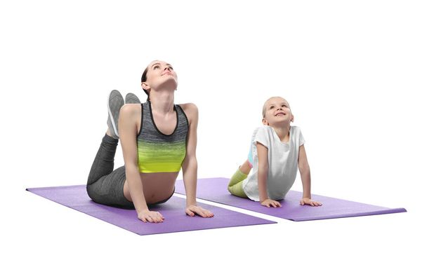 Mother and daughter doing exercise on white background - Fotó, kép