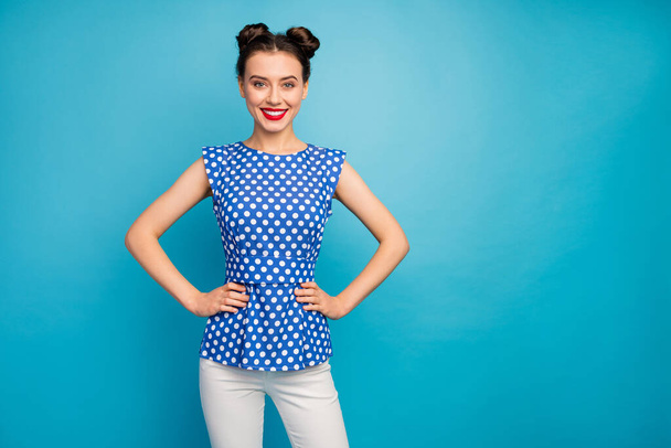 Photo of pretty confident lady red pomade hands by sides cheerful easy-going person beaming smiling wear dotted white blouse trousers isolated blue color background - Foto, afbeelding