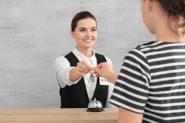 Recepcionista femenina dando llave de habitación de hotel a cliente
 - Foto, imagen