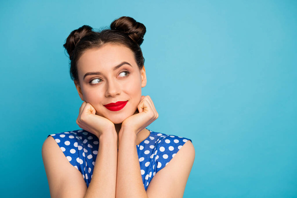 Closeup photo of pretty charming lady red pomade hands hold face overjoyed cute look side empty space interested wear dotted white retro blouse isolated blue color background - 写真・画像