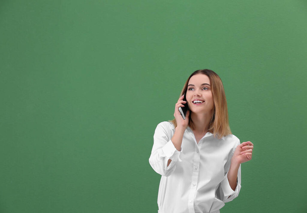Young woman using cell phone on green background - Foto, immagini