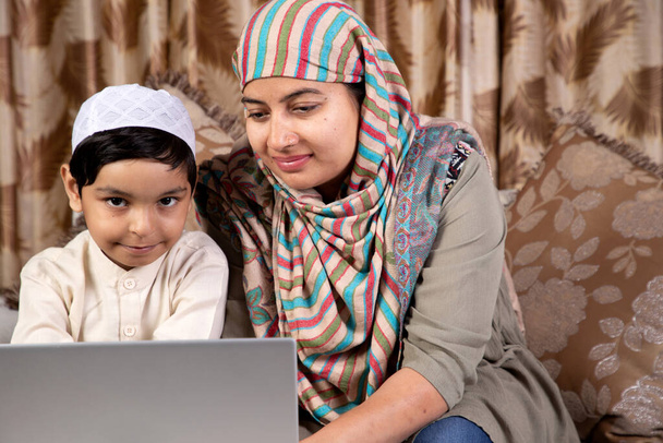 Matka uczy dziecko na laptopie lub notatniku w domu podczas okresu zamknięcia, nauczanie w domu - Zdjęcie, obraz
