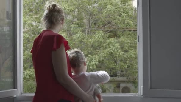 Mum with daughter taking the air in open window during coronavirus isolation - Filmati, video