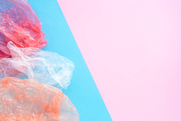 青とピンクの背景にコピースペースで砕いたビニール袋。ゴミの分別と保全生態学の概念。平文. - 写真・画像