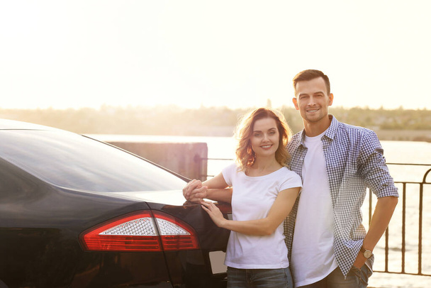 Όμορφο νεαρό ζευγάρι στέκεται κοντά στο αυτοκίνητο - Φωτογραφία, εικόνα