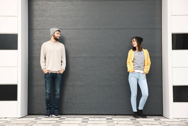 Trendy hipster paar poseren in de buurt van grijze muur - Foto, afbeelding