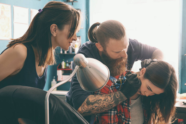 Profi tetoválóművész tanít gyakornokot a szalonban. A tanulószerződéses gyakorlati képzés fogalma - Fotó, kép