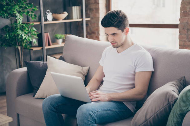 Portrait of his he nice attractive serious guy skilled it specialist sitting on divan working remotely preparing marketing presentation at modern industrial loft interior style living-room indoors - Photo, image