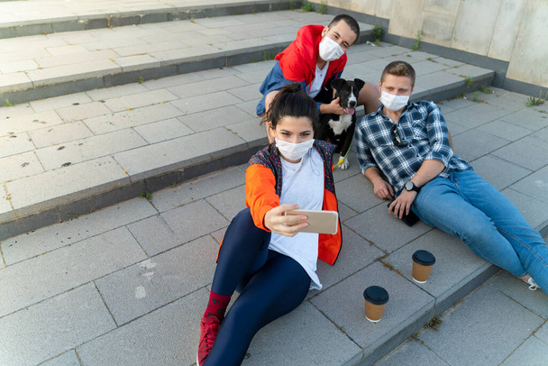 Wesoły student robi selfie z przyjaciółmi siedzącymi na schodach - Zdjęcie, obraz