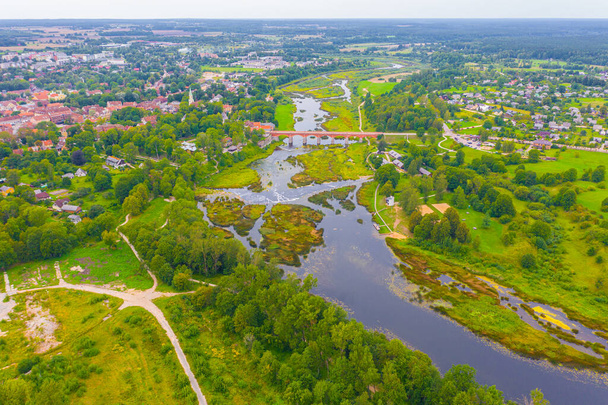 Όμορφη πανοραμική εναέρια άποψη φωτογραφία από ιπτάμενο drone να Venta Rapid καταρράκτη, το ευρύτερο καταρράκτη στην Ευρώπη και το τρίτο μεγαλύτερο τούβλο γέφυρα στην Ευρώπη σε μια καλοκαιρινή μέρα στην Kuldiga, Λετονία. (σειρά) - Φωτογραφία, εικόνα