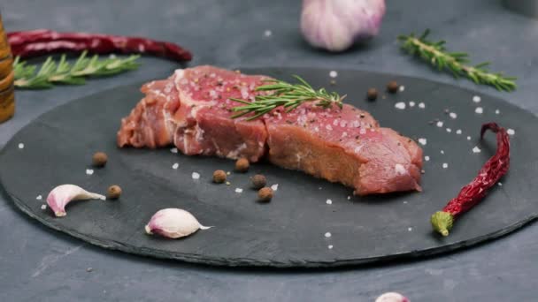 粗塩、コショウ、ローズマリーと石板上の柔らかい牛肉サーロイン. - 映像、動画