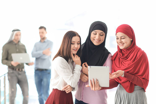Mulher de negócios muçulmana com colegas de trabalho em fundo leve
 - Foto, Imagem
